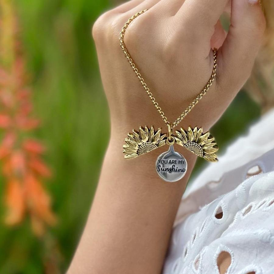 Two sunflower charms framing hidden inspirational quote on silver disc

