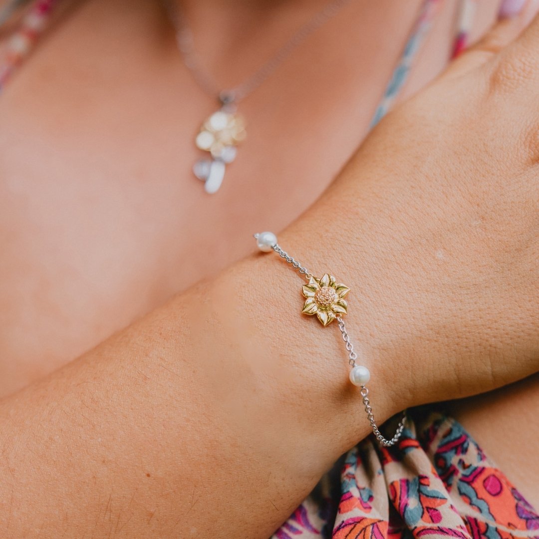 Elegant sunflower bracelet with gold-tone floral charm, silver chain, and delicate pearl accents – a perfect gift for women.

