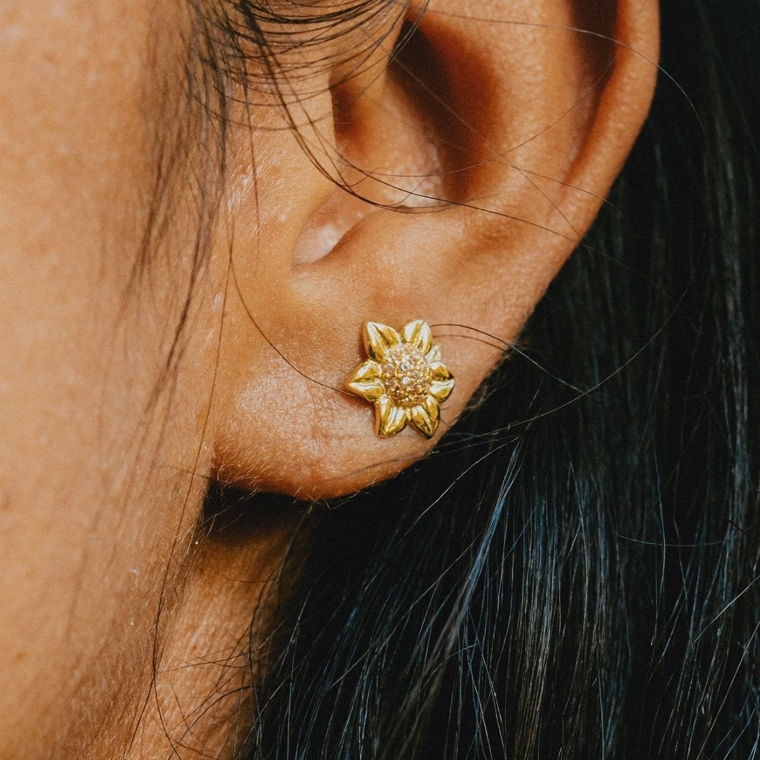 Elegant sunflower stud earrings in gold tone with sparkling crystal center, perfect for adding a touch of floral charm to any outfit.

