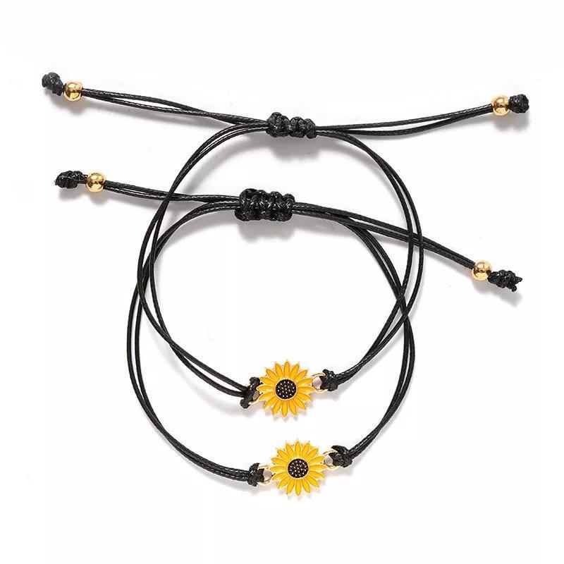 Matching sunflower charm bracelets with adjustable black cord, presented on a sentimental card for best friends or sisters. Perfect long-distance friendship gift to show love and connection.

