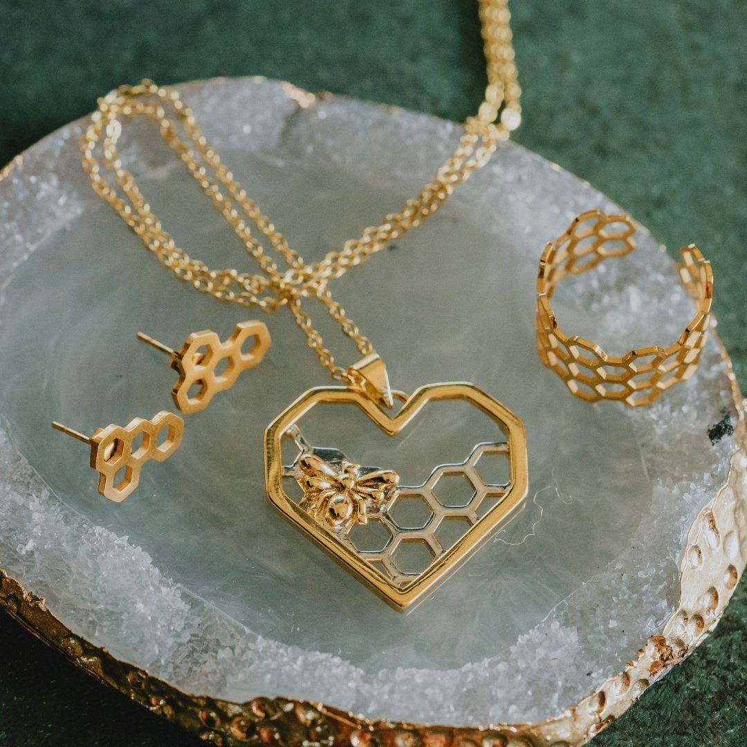 Nature-inspired gold jewelry set featuring bee heart necklace and honeycomb designs

